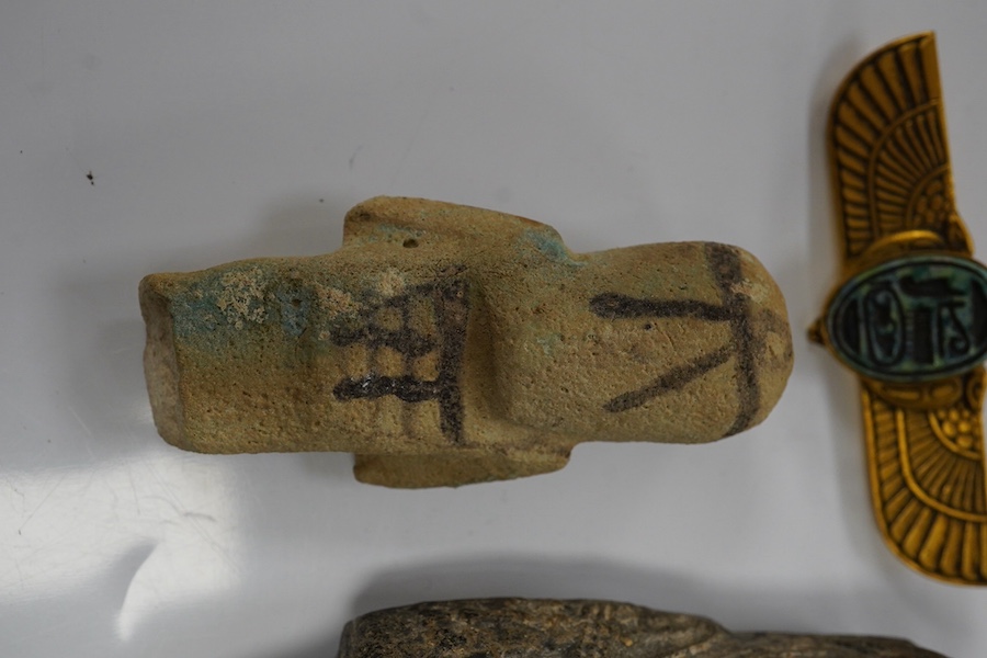 Three ancient Egyptian carved stone ushabti, tallest 15cm, with carved hieroglyphs to the body, together with a seated figure, possibly of Isis, a scarab and a yellow metal brooch with inset stone carved with hieroglyphs